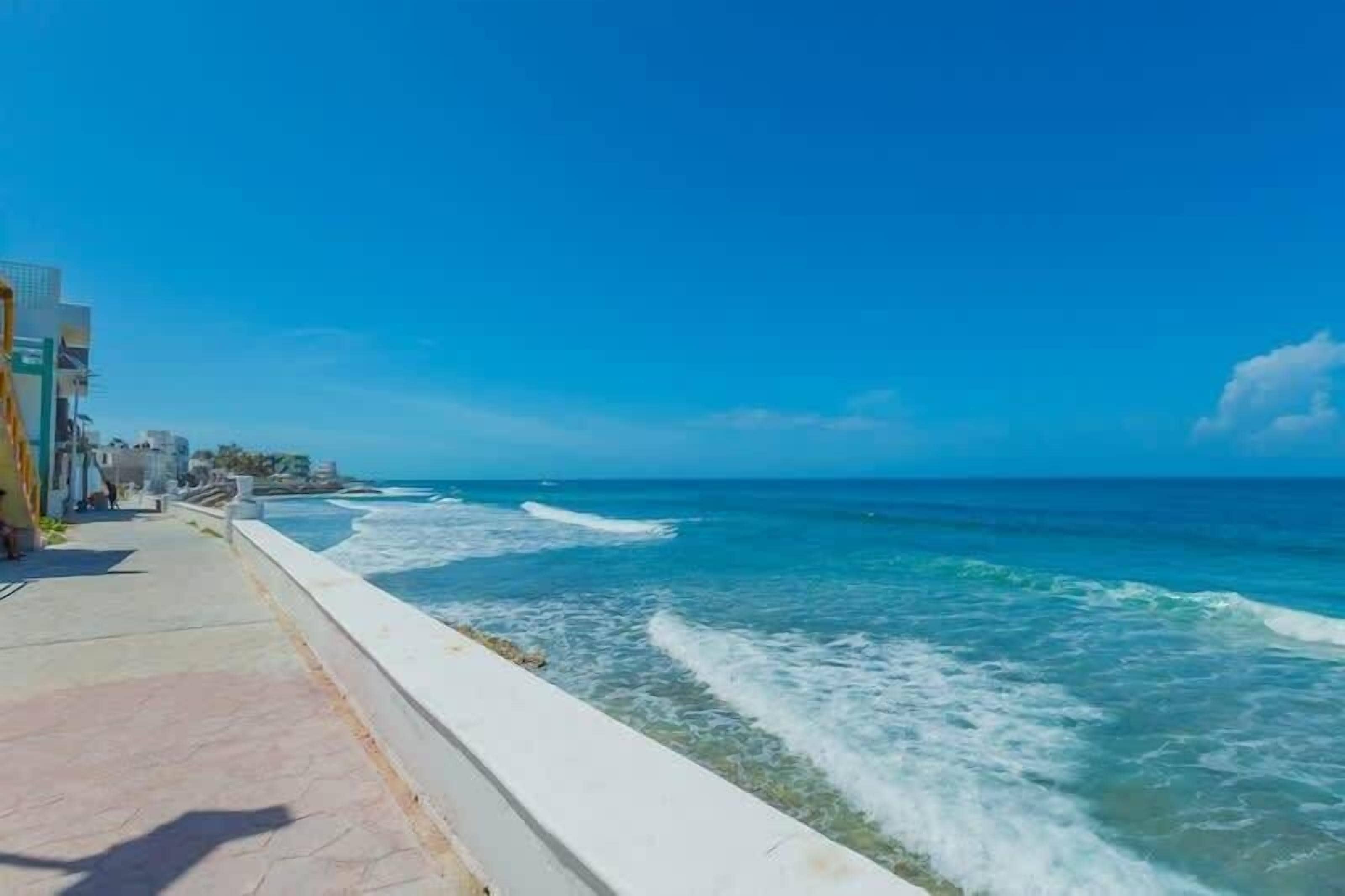 A coastal walkway with a view of the ocean and buildings along the side.