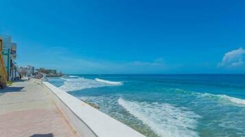 A coastal walkway with a view of the ocean and buildings along the side.