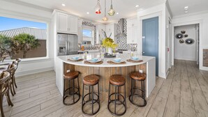 A modern kitchen with white cabinetry, a central island with stools, and pendant lighting.