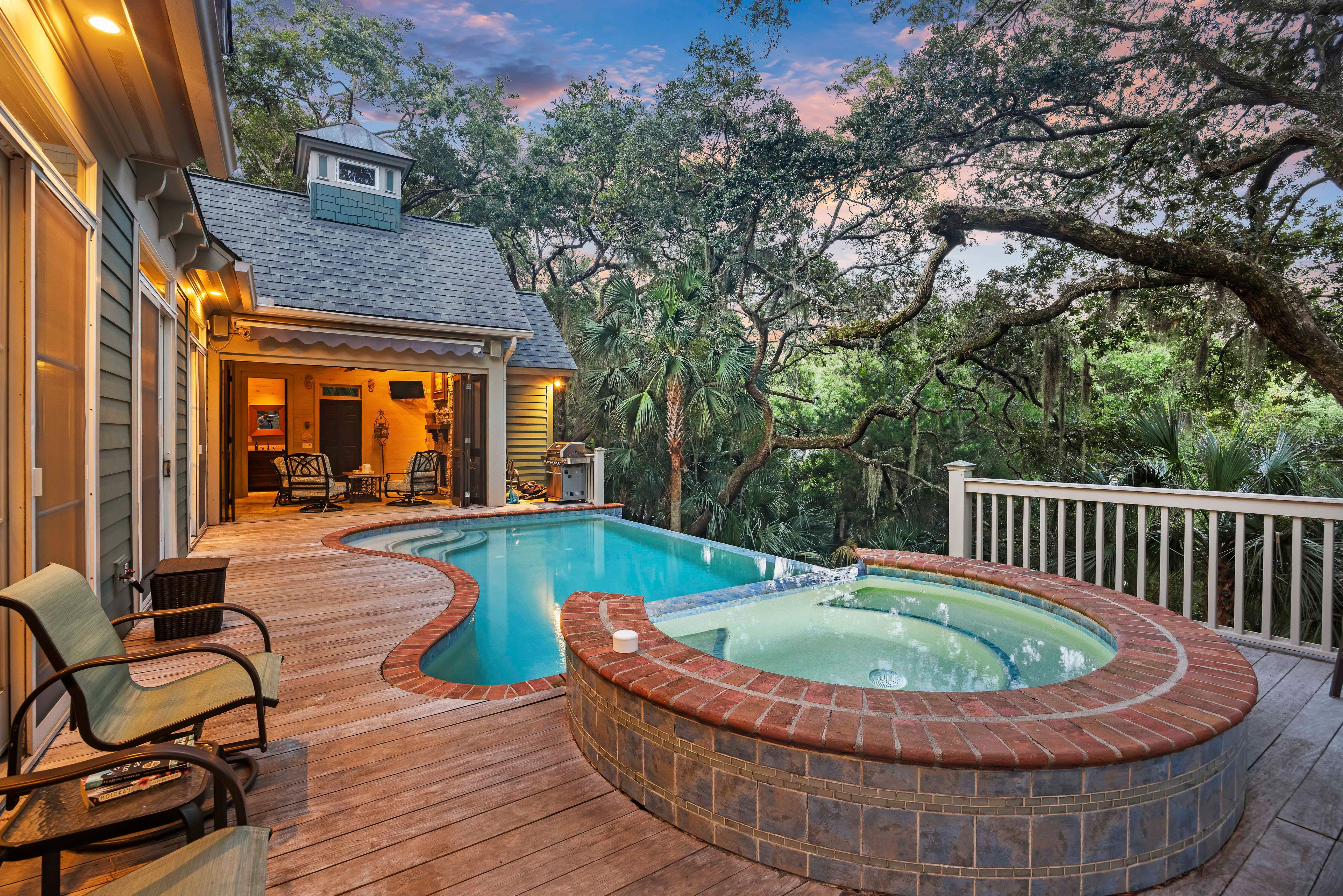 A backyard with a hot tub, wooden deck, and outdoor seating area.