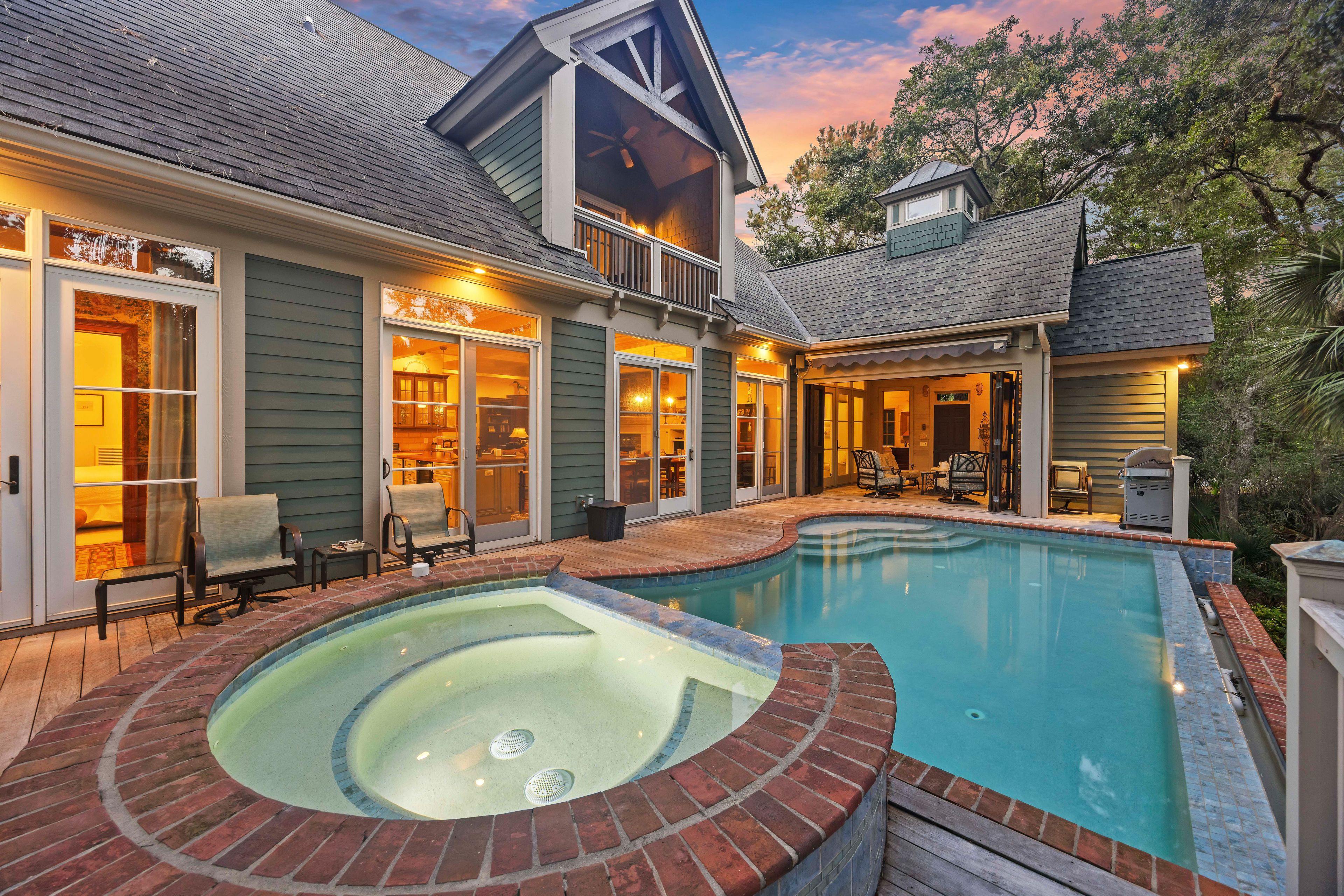 Ein Wohnhaus mit Swimmingpool, Sitzgelegenheiten im Freien und einer überdachten Terrasse.