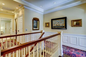 A staircase with white balusters and a wooden handrail, leading to a landing with a patterned carpet.