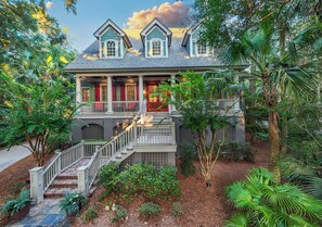 A two-story house with a porch, a staircase, and a garden with various plants.