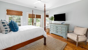 A bedroom with a four-poster bed, a television, a chair, and a window with a view. - Private heated pool + 1 block from beach + Pet Friendly (Folly Beach)