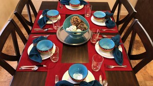 Ein Esstisch ist gedeckt mit blauen Schüsseln, Tellern und Besteck, in der Mitte eine Schale mit Snacks.