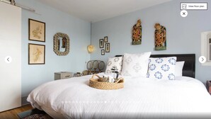 A bedroom with a bed, a bedside table, a lamp, and wall decorations.