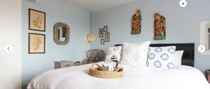 Un dormitorio con cama, mesita de noche, lámpara y adornos en la pared.