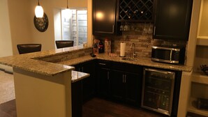 A kitchen with dark cabinets, a granite countertop, a built-in microwave, and a wine rack. - - Pikes Peak/Garden of the Gods!  Booking FAST! (Colorado Springs)