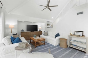 Ein modernes Wohnzimmer mit Sofa, Couchtisch, Fernseher und Bücherregal.
