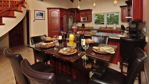 Ein Essbereich mit einem Glastisch, Ledersesseln und Holzschränken.