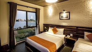 Hotelkamer met een groot bed, nachtkastje met telefoon, raam met gordijnen, bakstenen muur en een fotolijst.