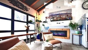 Un salon chaleureux avec une cheminée, des sièges confortables et de grandes fenêtres.
