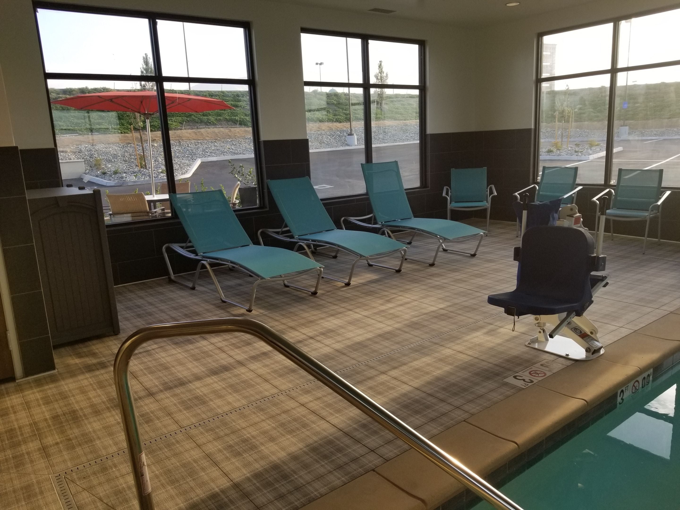 Zona de piscina con sillones de descanso, una piscina y vistas al exterior.