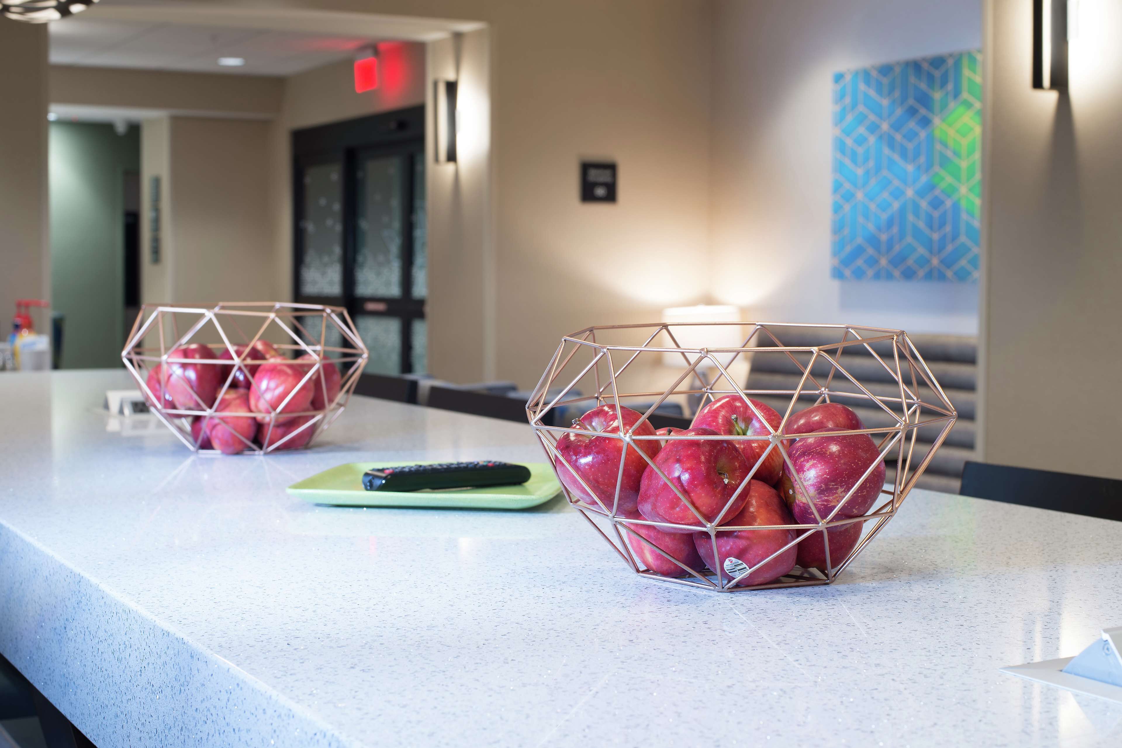 Two wire baskets containing apples on a countertop.