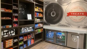 Quiosco de aperitivos y bebidas con estantes llenos de diferentes productos y un letrero que dice 'Treats'.