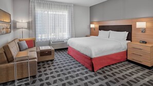 A hotel room with a bed, a sofa, a nightstand, and a lamp. - TownePlace Suites by Marriott Edmonton Sherwood Park (Sherwood Park)