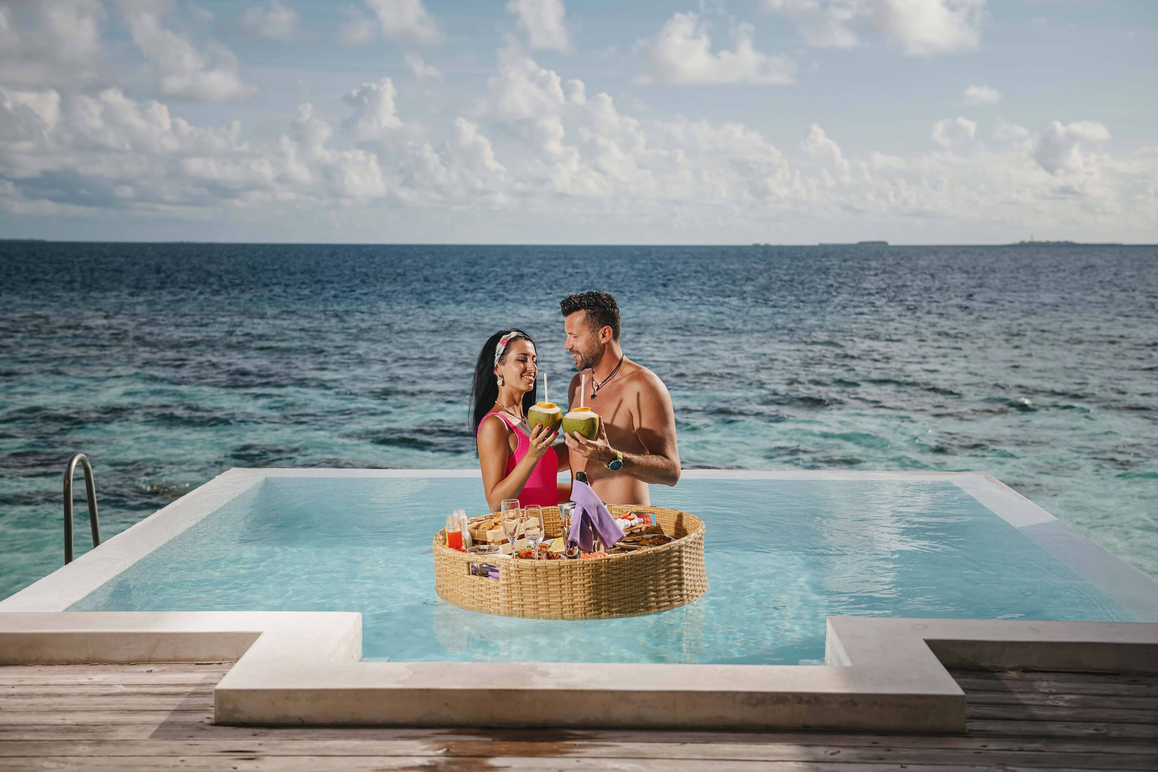 Una pareja junto a una piscina con vista al océano.