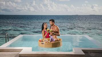 Una pareja junto a una piscina con vista al océano.