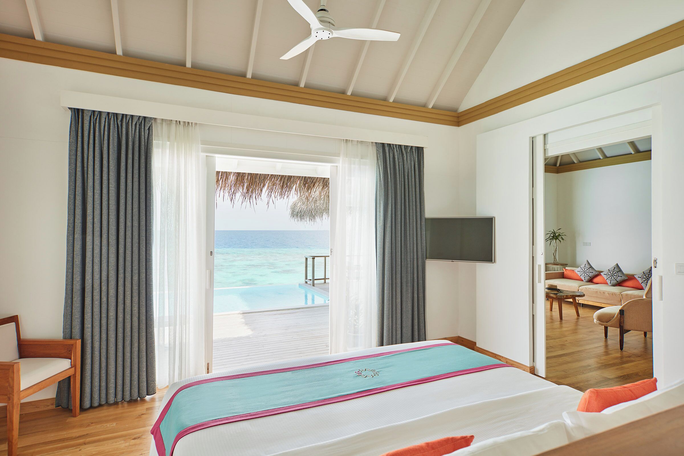 A bedroom with a bed, a TV, and a view of the ocean.