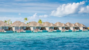 Overwater bungalows with thatched roofs, connected by walkways, set against a turquoise sea and clear sky. - Sun Siyam Iru Veli - 24 Hours All-Inclusive (Aloofushi)