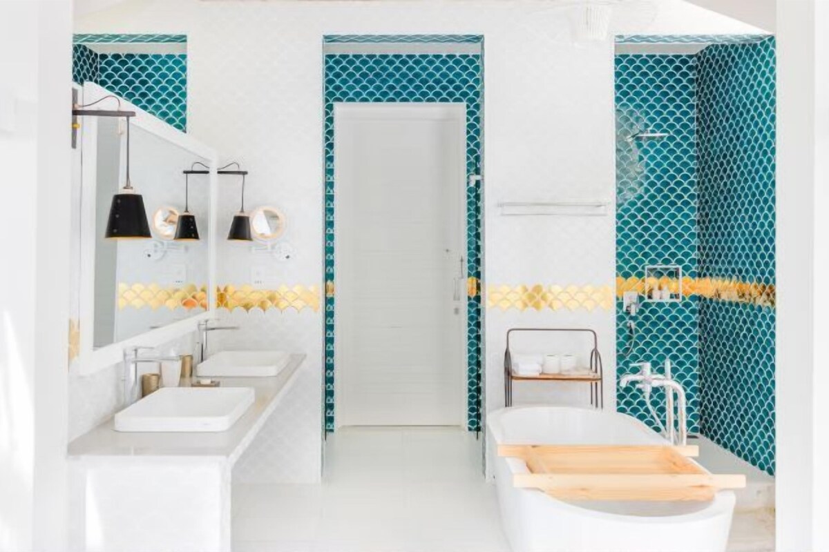 A modern bathroom with two sinks, a bathtub, and a shower area.