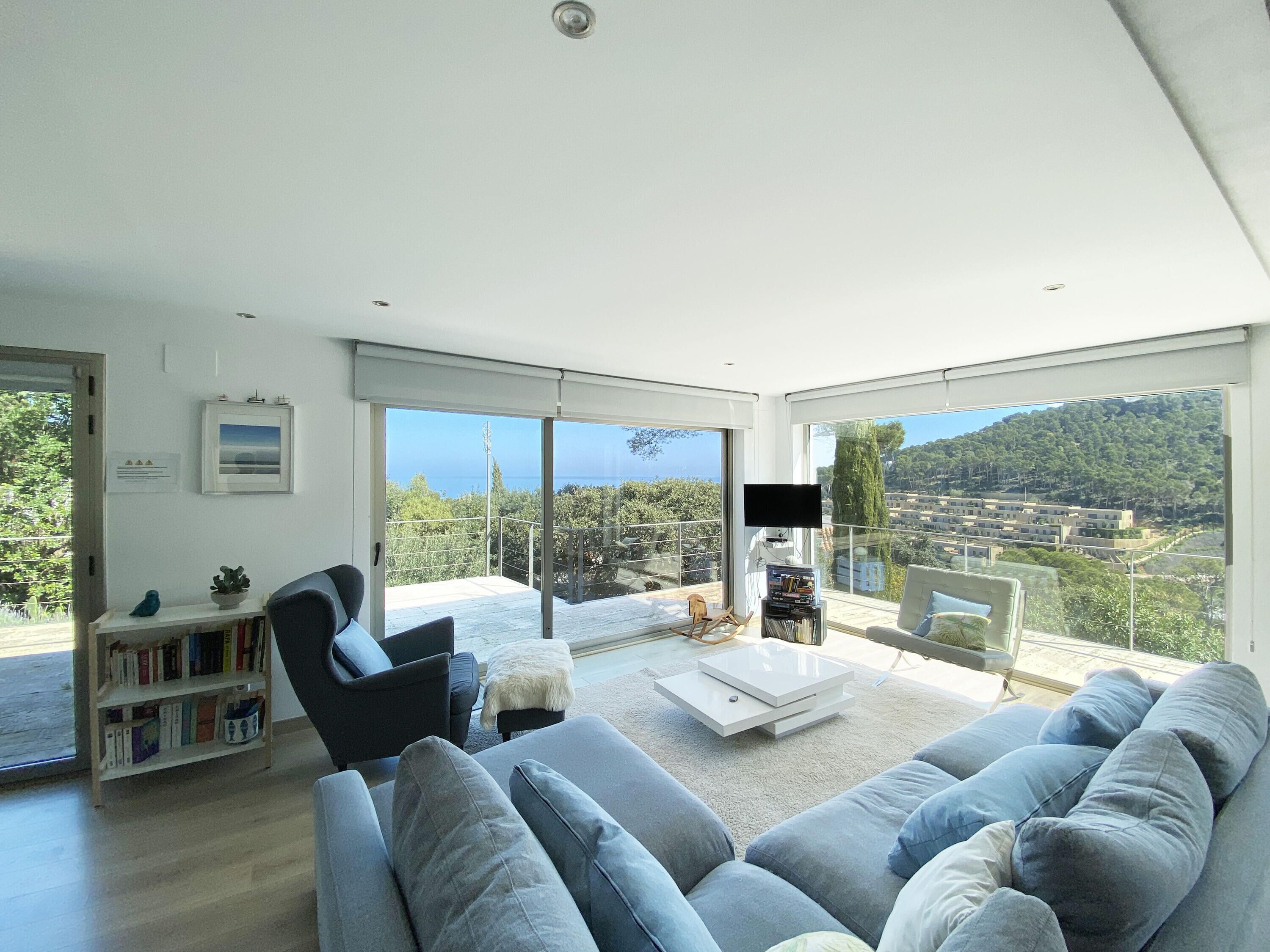 A modern living room with a large grey sofa, a coffee table, and a bookshelf.