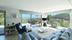 A modern living room with a large grey sofa, a coffee table, and a bookshelf. - Holiday rental villa with swimming pool in Begur, Sa Riera (Begur)
