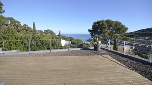 A wooden deck with a railing, a potted plant, and a view of the sea and hills. - Holiday rental villa with swimming pool in Begur, Sa Riera (Begur)