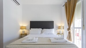 A neatly made bed with white linens, two bedside lamps, and a large window with curtains. - Atico de los FRANCESES by Cadiz4Rentals (Cádiz)