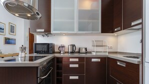 A modern kitchen with a built-in microwave, coffee maker, and toaster. There are wooden cabinets and a stainless steel range hood. - Atico de los FRANCESES by Cadiz4Rentals (Cádiz)