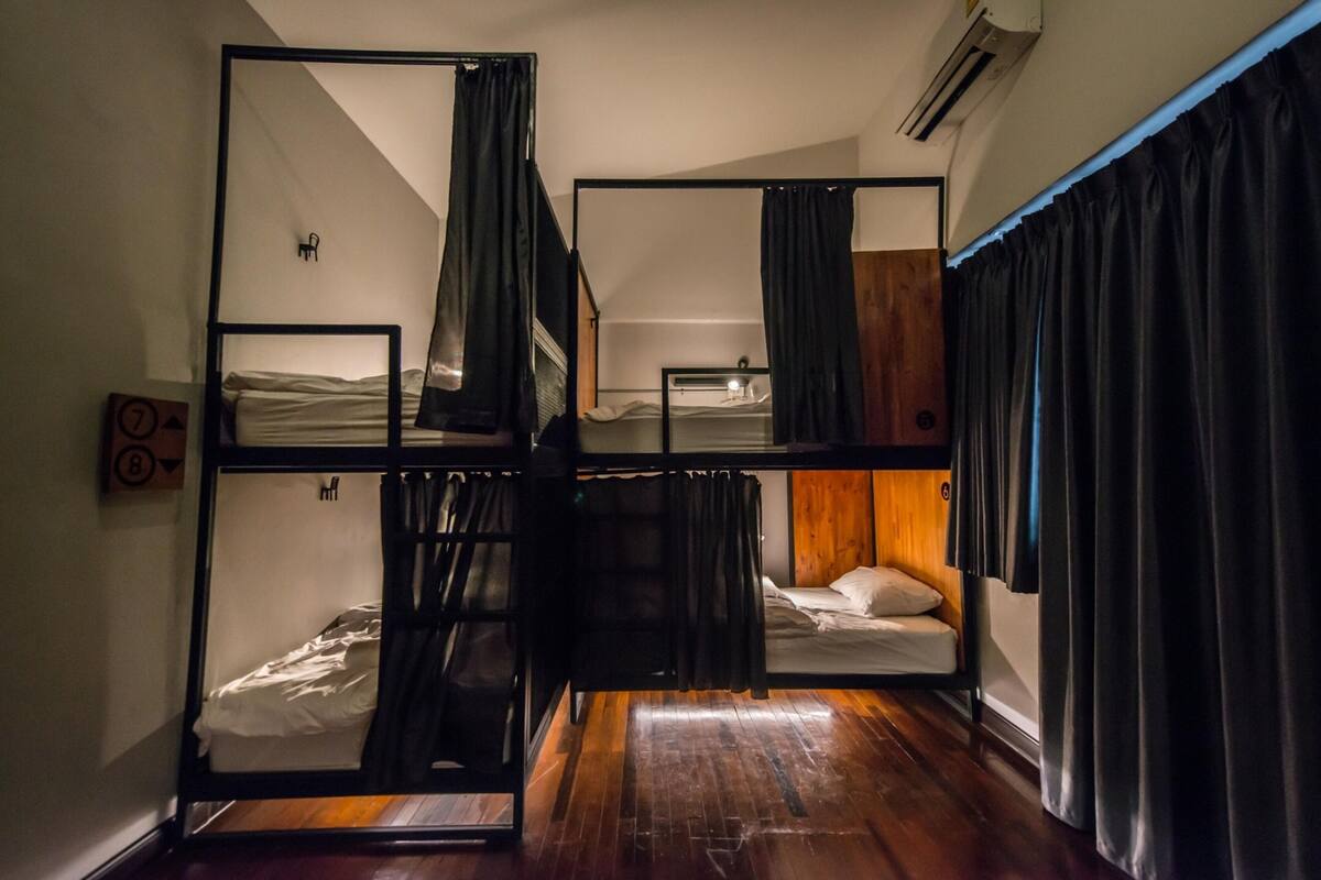 Ein Zimmer mit Etagenbetten, Holzboden und Spiegel an der Wand.