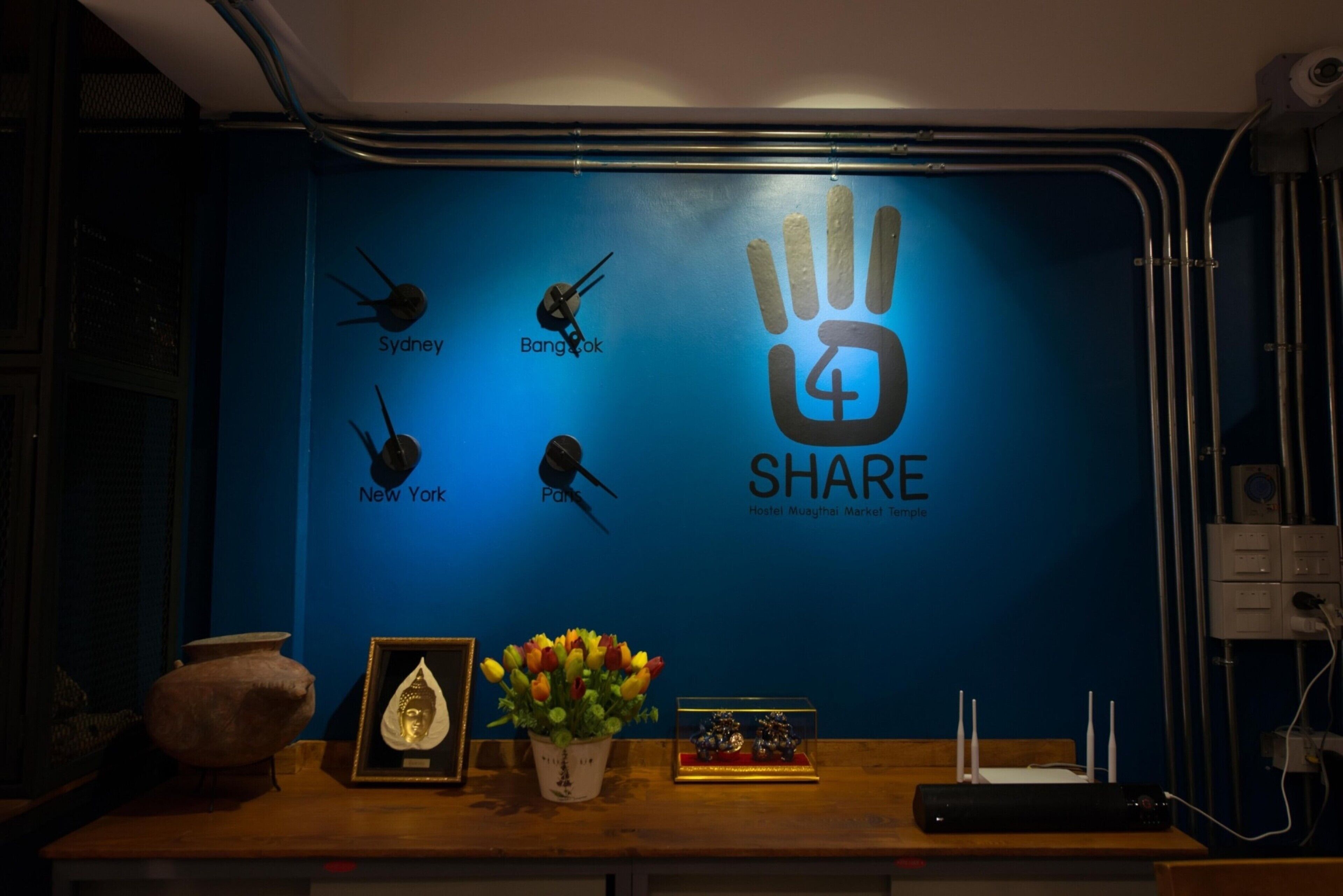 Un mur avec un fond bleu, orné d  ’une empreinte de main et du mot « PARTAGER », avec les noms des villes suivantes écrits en dessous : Sydney, Bangkok, New York et Paris.