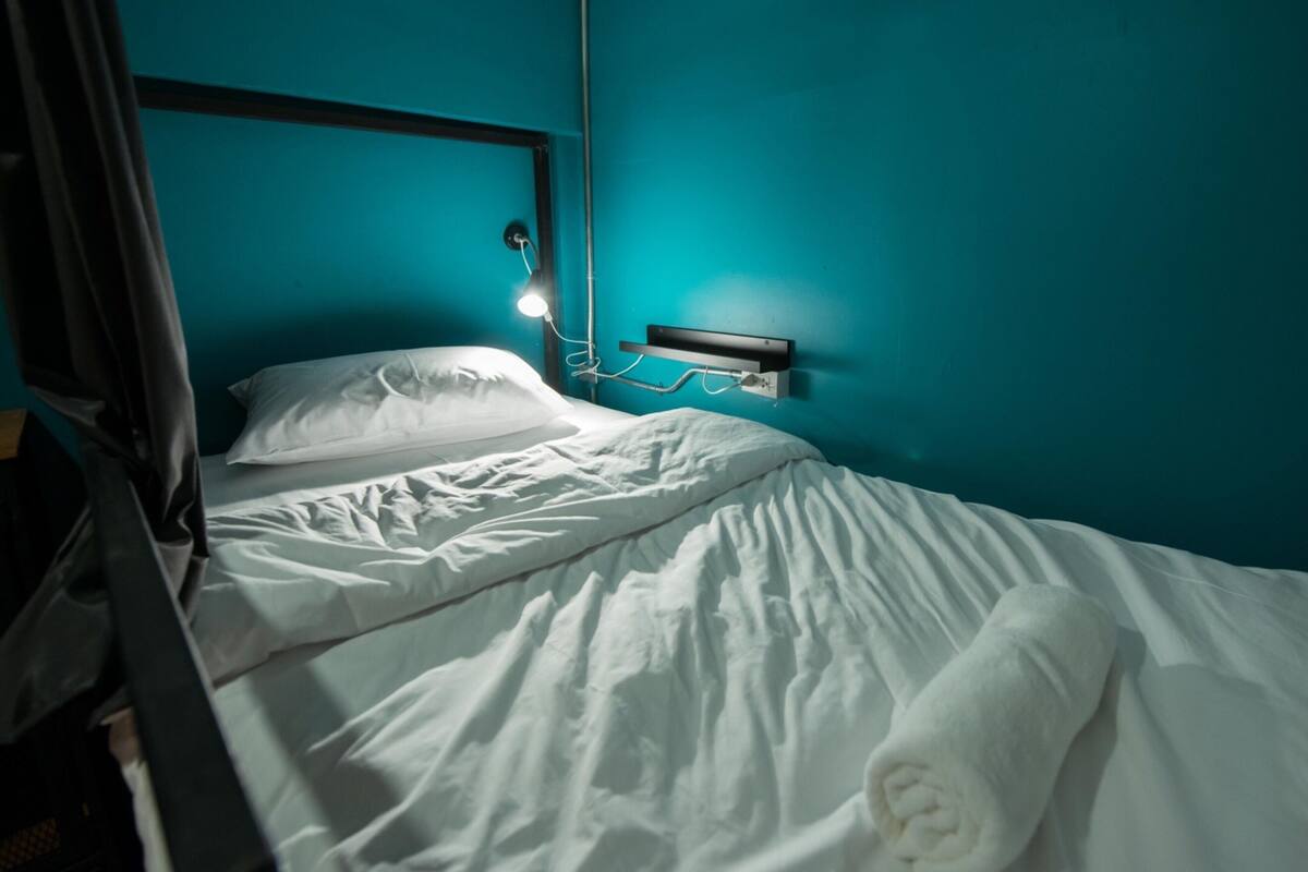 Ein Bett mit weißer Bettwäsche, einem Kopfteil und einer Wandleuchte.