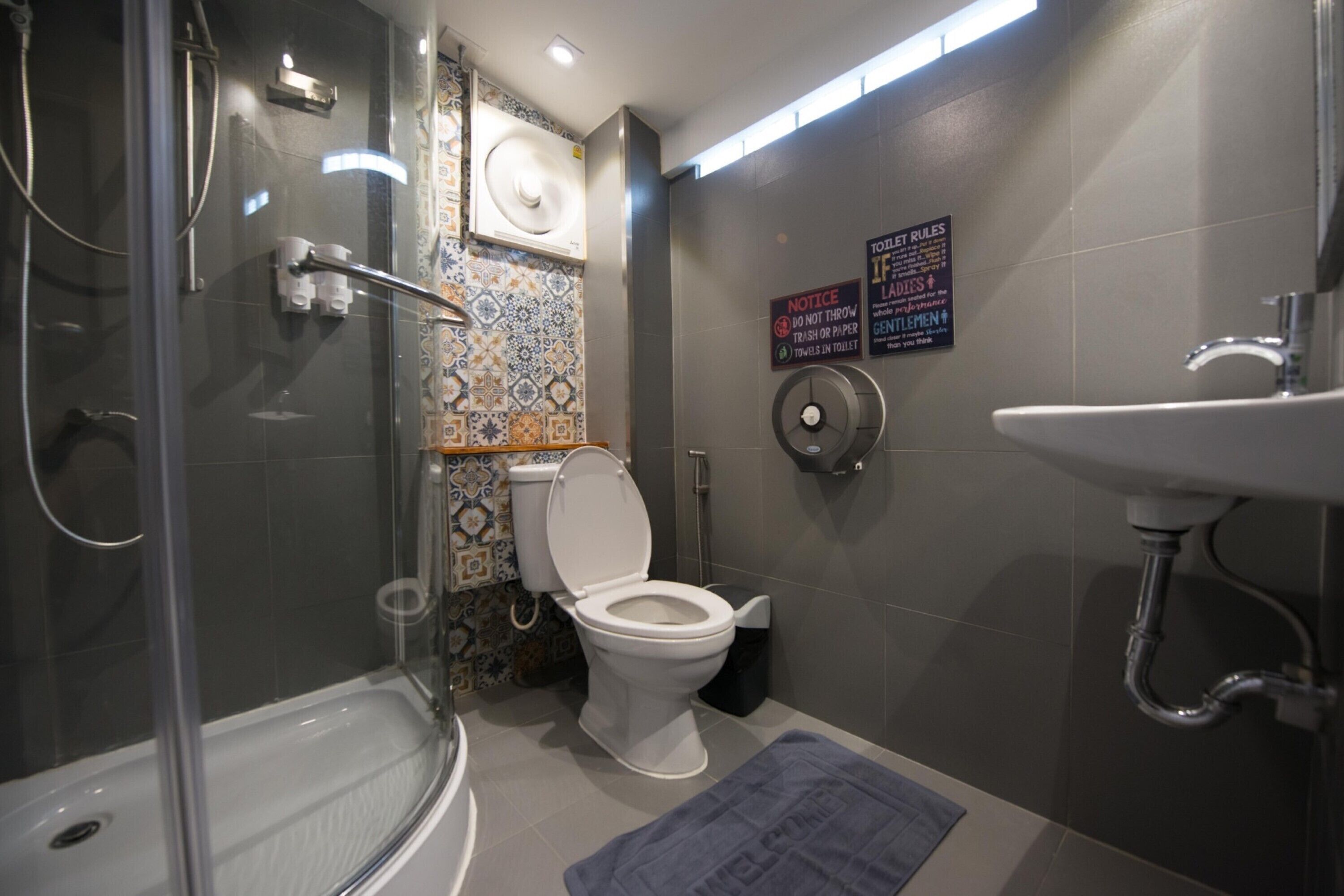Un baño moderno con ducha envuelta en vidrio, un inodoro blanco y un lavamanos.
