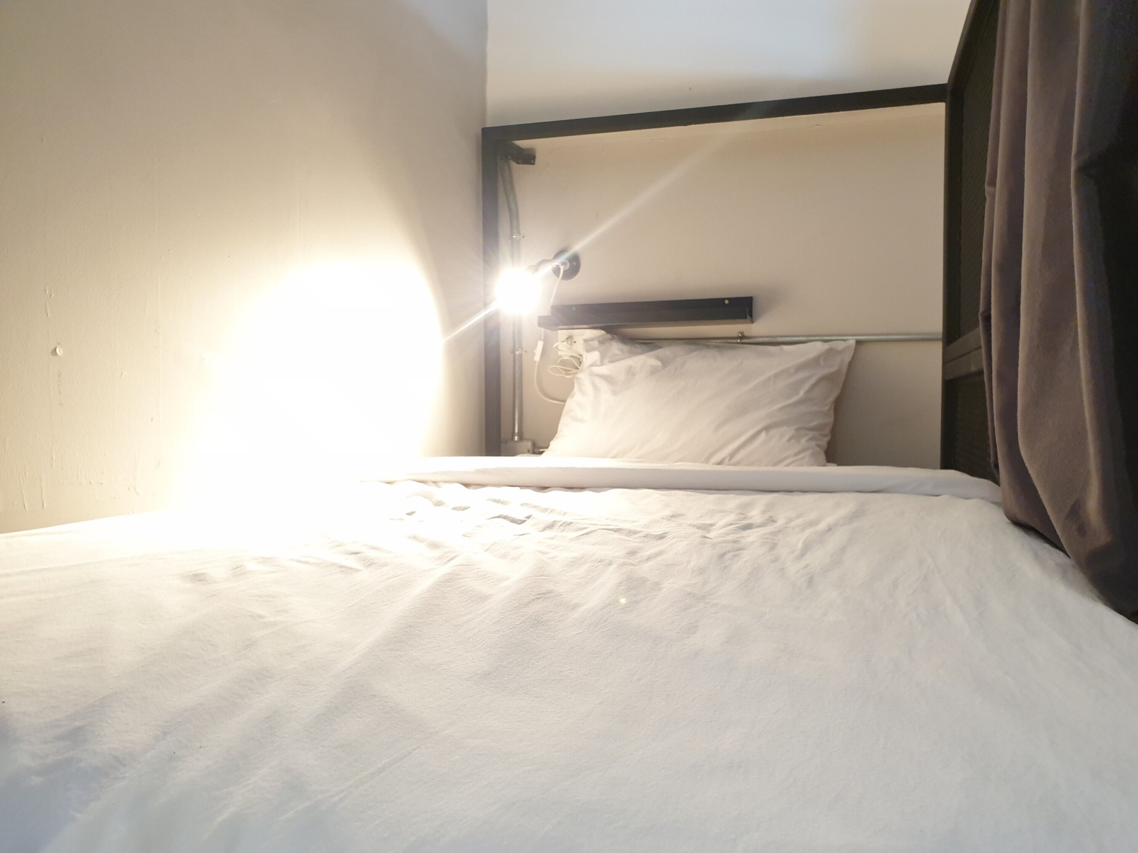 A single bed with a headboard, a bedside table, and a lamp.