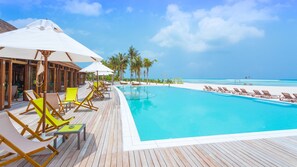 Una piscina al aire libre, sombrillas, sillones reclinables de piscina