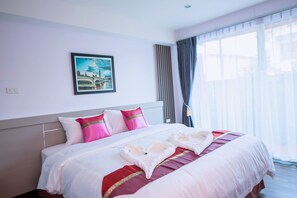 A hotel room with a neatly made bed, a framed picture on the wall, and a large window with curtains.
