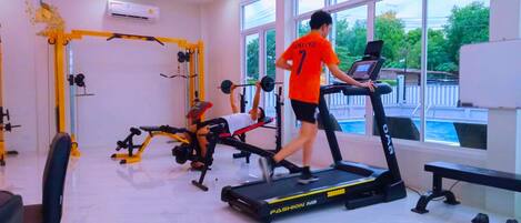 A gym with exercise equipment, a treadmill, and large windows.
