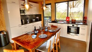 Une cuisine moderne avec des meubles en bois, des appareils en acier inoxydable et une grande table à manger pouvant accueillir six personnes.