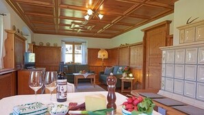 Un comedor con una mesa de madera preparada para una comida, un sofá al fondo y una zona de cocina con armarios de madera.