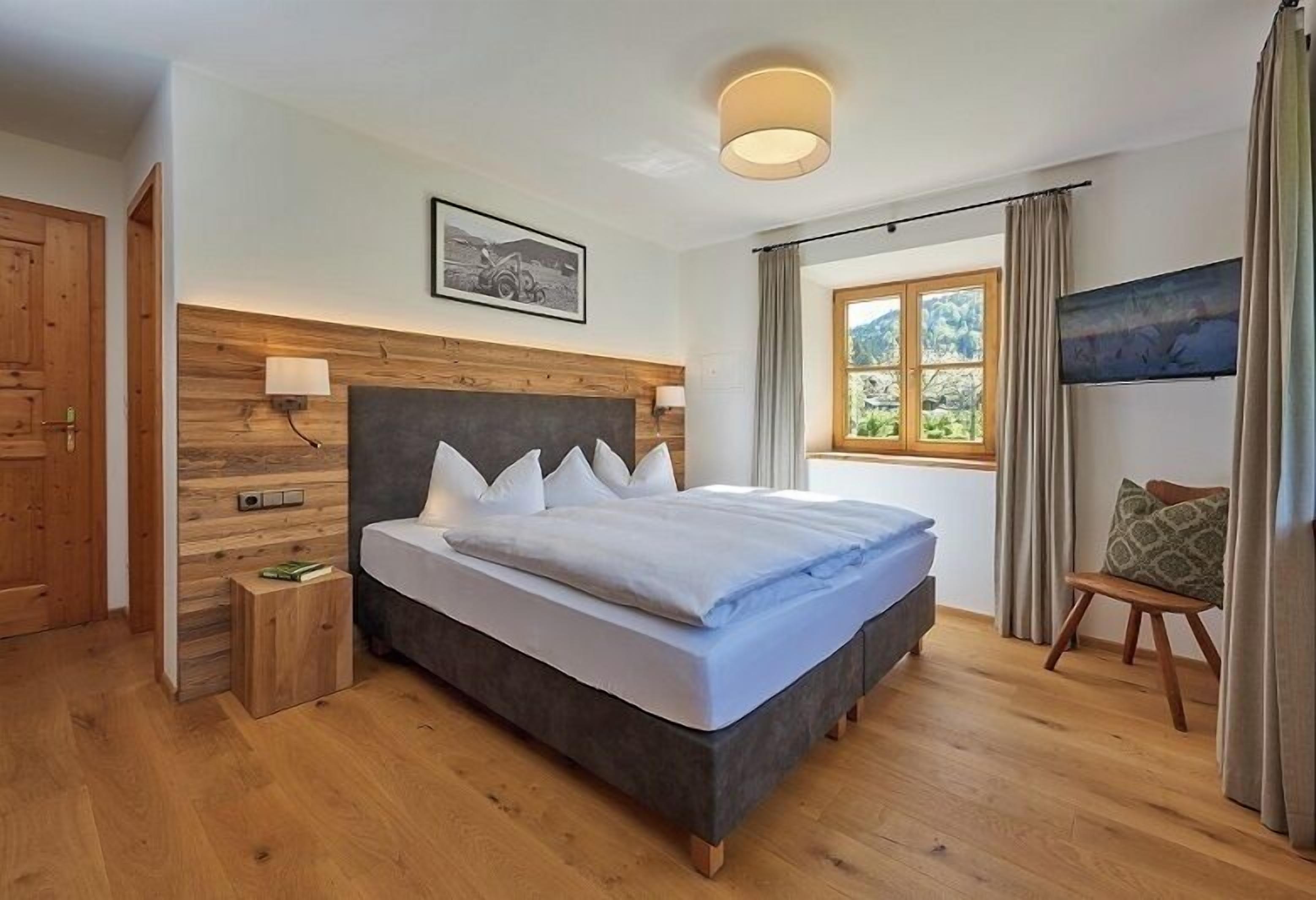 Camera da letto moderna con un letto grande, una testiera in legno e una finestra con tende.