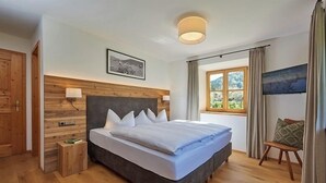 Un dormitorio moderno con una cama grande, cabecera de madera y una ventana con cortinas.