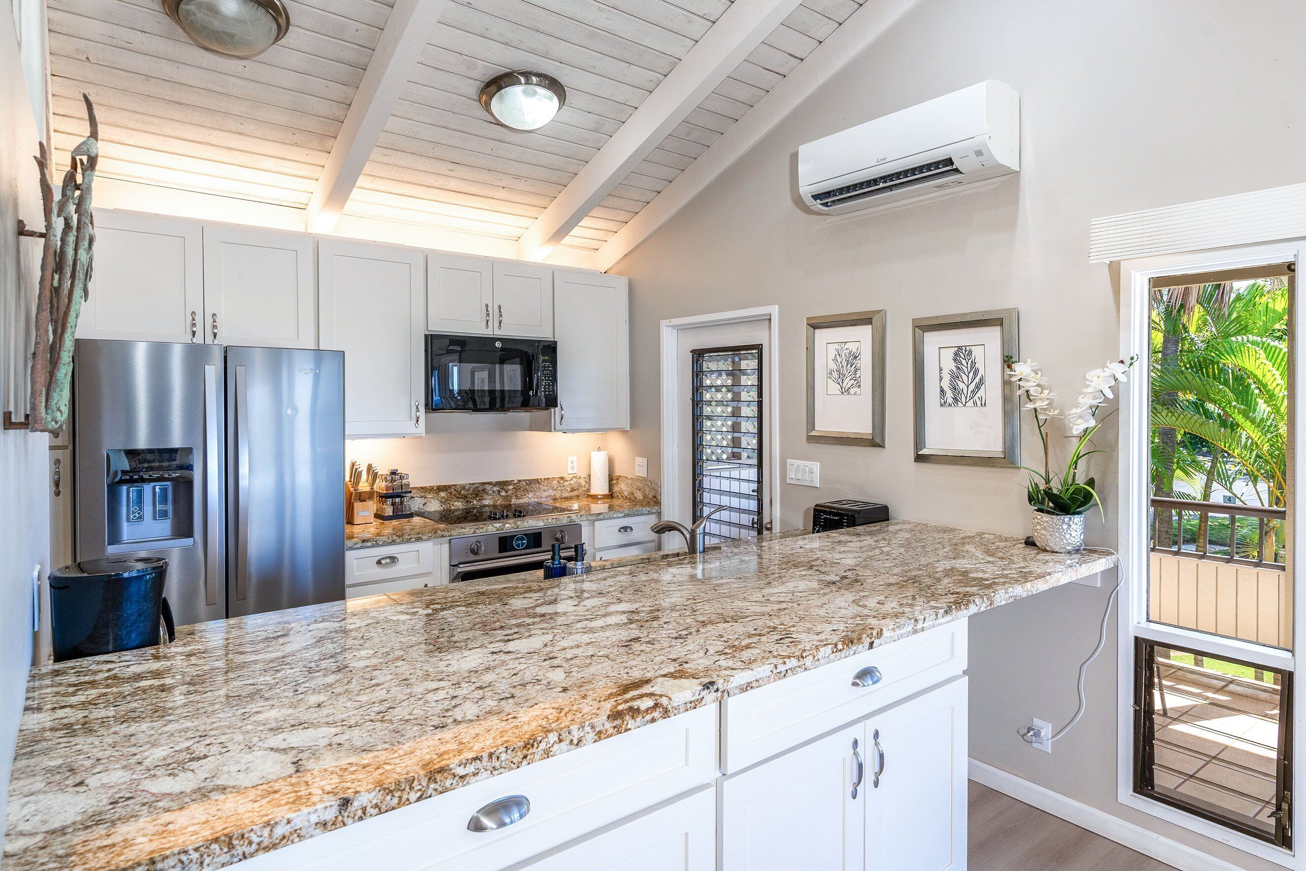 A kitchen with granite countertops, stainless steel appliances, and white cabinetry.
