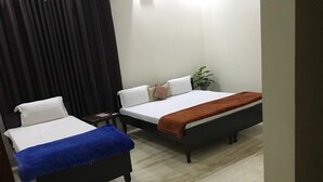 A bedroom with two beds, a small table, and a potted plant. - Winsome Guest House (Noida)