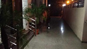 A corridor with a potted plant, a metal railing, and a wall with a window. - Winsome Guest House (Noida)