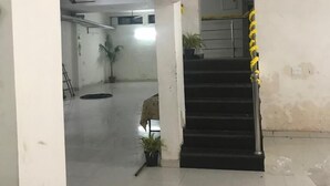 A hallway with a staircase, white walls, and a ceiling fan. - Winsome Guest House (Noida)
