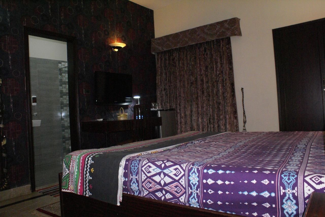 A hotel room with a bed, a desk, a television, and a curtain.