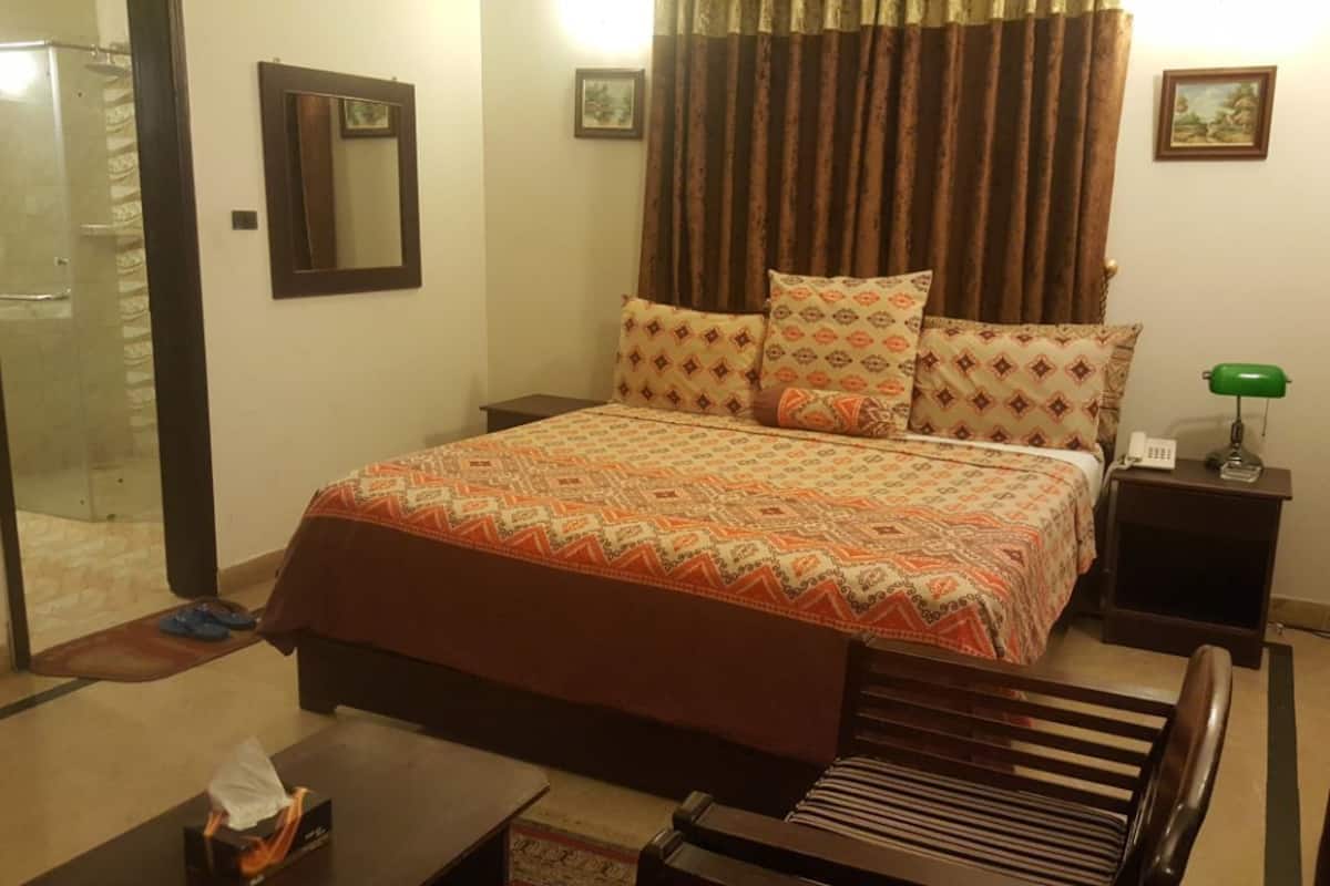 A neatly arranged bedroom with a bed, bedside table, and a chair.