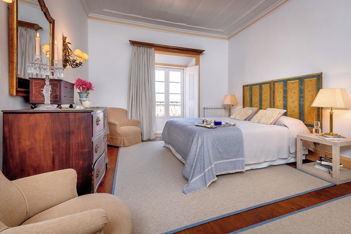 A bedroom with a bed, bedside table, dresser, and a large mirror.
