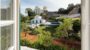 A courtyard with a white building, a yellow church, and a stone wall.